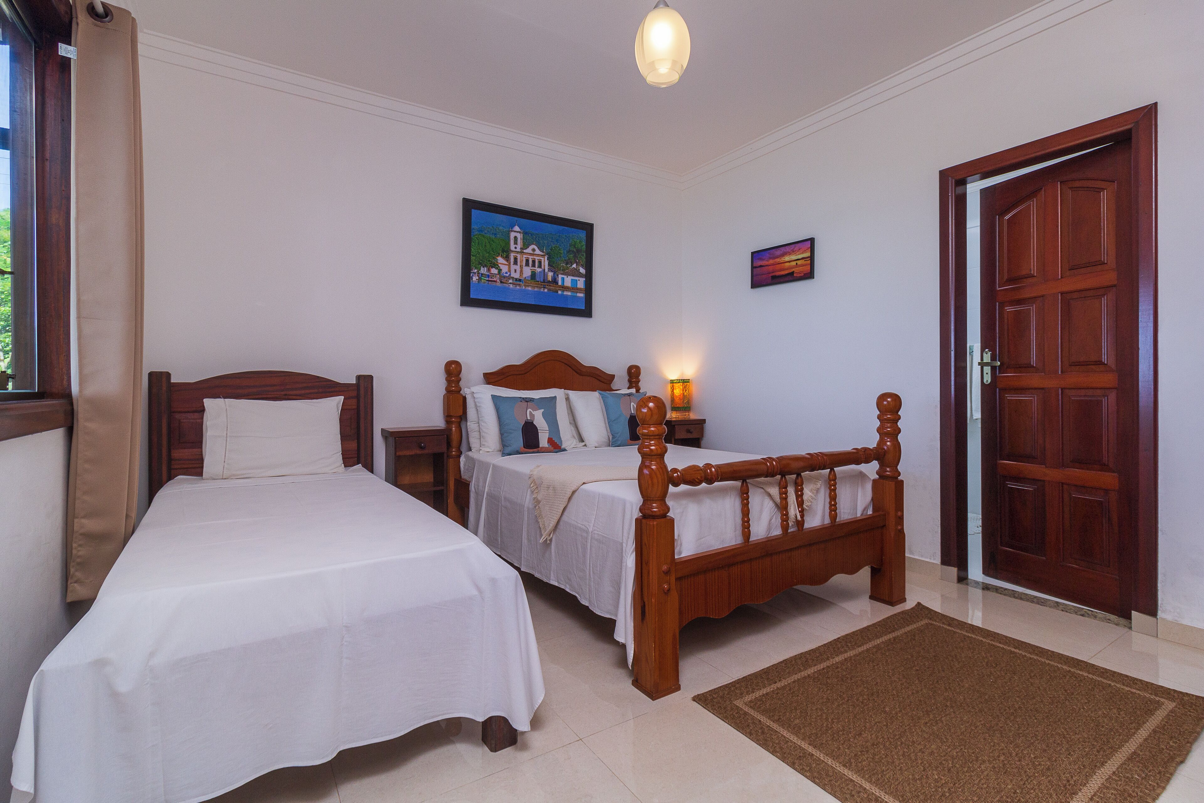 A bedroom with two single beds, a wooden headboard, a nightstand, a lamp, and a door.