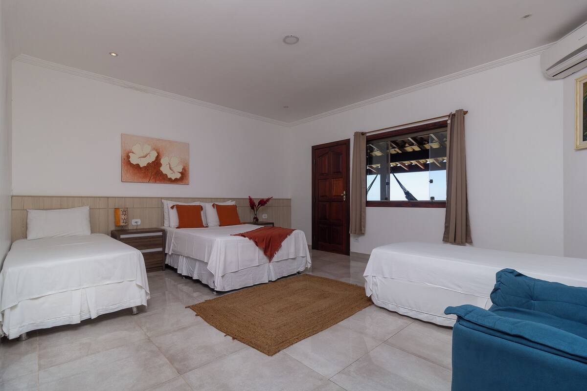 Une chambre d’hôtel avec deux lits, un canapé, une table de chevet en bois, un tapis marron et un tableau au mur.