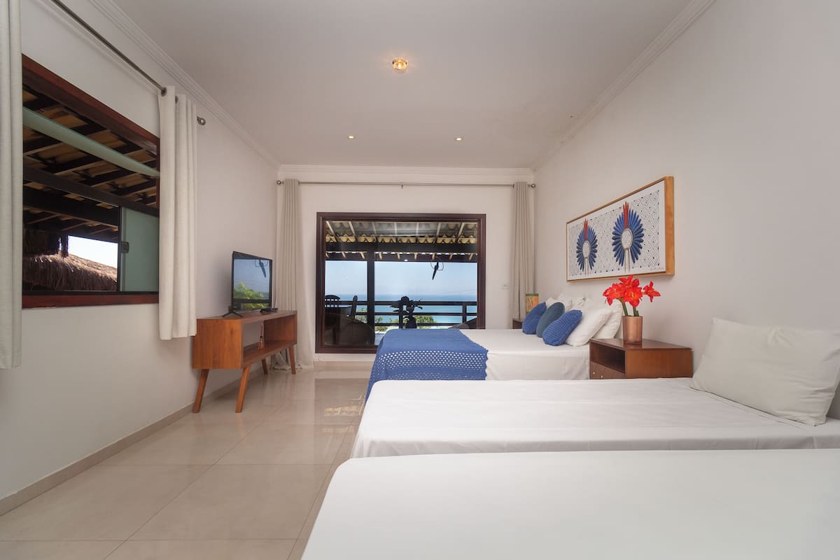 Une chambre d’hôtel avec deux lits, une télévision, une fenêtre donnant sur un beau paysage et un tableau au mur.
