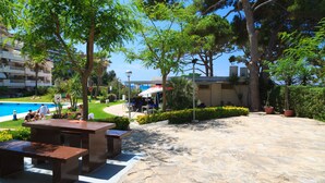Eine Außenpatio-Terrasse mit Steinboden, Bänken und Topfpflanzen.