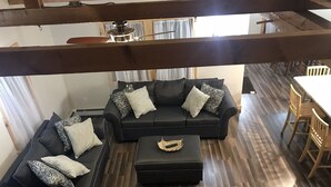Een moderne woonkamer met een hoekbank, een voetenbankje en een houten eettafel.