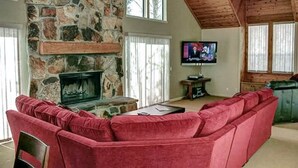 A cozy living room with a stone fireplace, a red sofa, and a television.