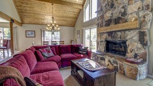 A cozy living room with a stone fireplace, a large sectional sofa, and a chandelier.