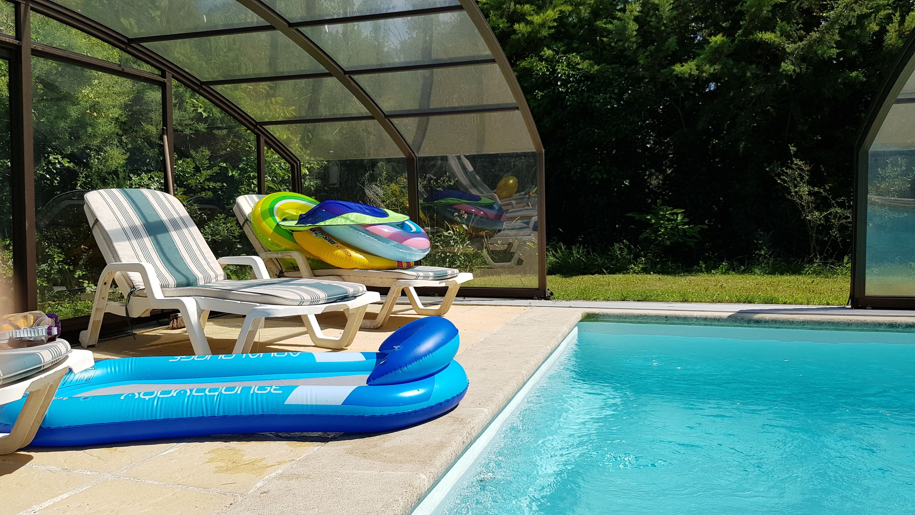 Un espace aménagé au bord de la piscine, avec des chaises longues et des piscines gonflables.
