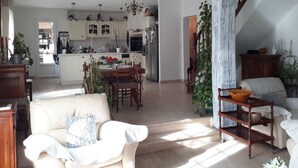 En rummelig opholdsstue med spisebord, sofa og trappe op til et repos.