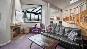 Un salon spacieux avec une cheminée, un canapé en cuir et un escalier en bois.