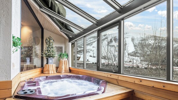 Un bain à remous installé dans un coin, avec une grande fenêtre donnant sur un paysage enneigé.