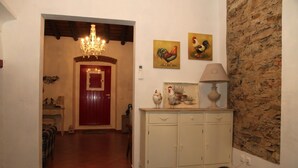 Passadís amb un candelabrum, una porta vermella i un armari blanc decorat amb objectes.