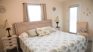A bedroom with a bed, nightstands, a chair, and a door.