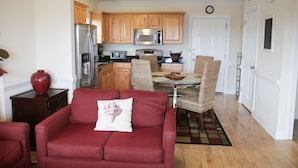 A modern kitchen with wooden cabinets, stainless steel appliances, and a dining area with wicker chairs.