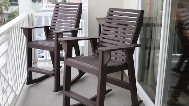 A balcony with two rocking chairs and a glass door.