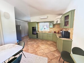 A compact kitchen with green cabinets, a black refrigerator, a microwave, and a sink. - Villa "ARCA" – Warmth, tranquility and heated pool in Porto-Vecchio (Sotta)