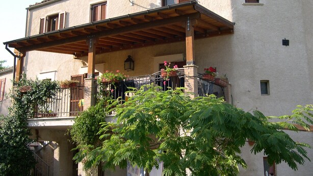 A two-story building with a balcony, potted plants, and a satellite dish.