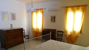 A bedroom with a bed, dresser, chair, and curtains.