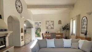 A spacious living room with a large sectional sofa, a fireplace, and a dining area with a table and chairs. - Air-conditioned villa, 4-star rating, Ste-Maxime residential area, golf view (Sainte-Maxime)