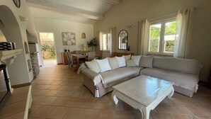 A spacious living area with a large beige sectional sofa, a white coffee table, and a dining area with a wooden table and chairs. - Air-conditioned villa, 4-star rating, Ste-Maxime residential area, golf view (Sainte-Maxime)