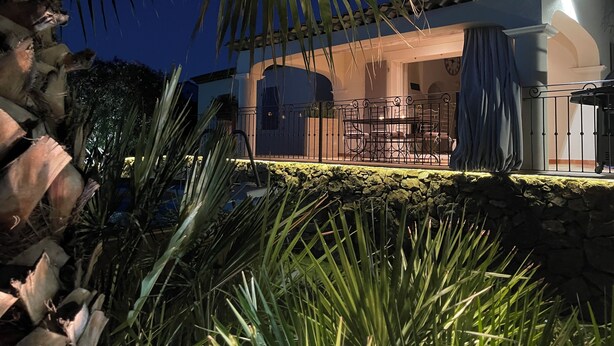 A well-lit outdoor patio area with a stone wall, a dining table with chairs, and a covered seating area. - Air-conditioned villa, 4-star rating, Ste-Maxime residential area, golf view (Sainte-Maxime)