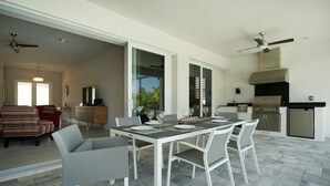 Ampla sala de estar com mesa de jantar para quatro pessoas, cozinha equipada com eletrodomésticos modernos e varanda com vista.