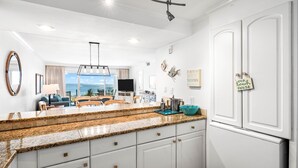 A modern kitchen with granite countertops, white cabinetry, and a view of the ocean. - Beach House 103D  - Ground Floor - Beachfront! (Miramar Beach)