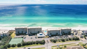 A beachfront hotel with multiple buildings, a swimming pool, and a tennis court. - Beach House 103D  - Ground Floor - Beachfront! (Miramar Beach)