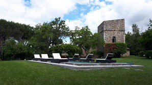 A pool area with lounge chairs and a stone building in the background.