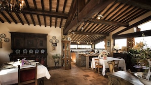 A rustic dining area with wooden beams, a central island with a sink, and a variety of dishes displayed on the walls.