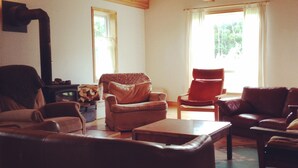 Una sala de estar acogedora con chimenea, techo de madera y ventanas amplias.
