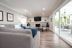 Een woonkamer met een open haard, een televisie en een groot raam.