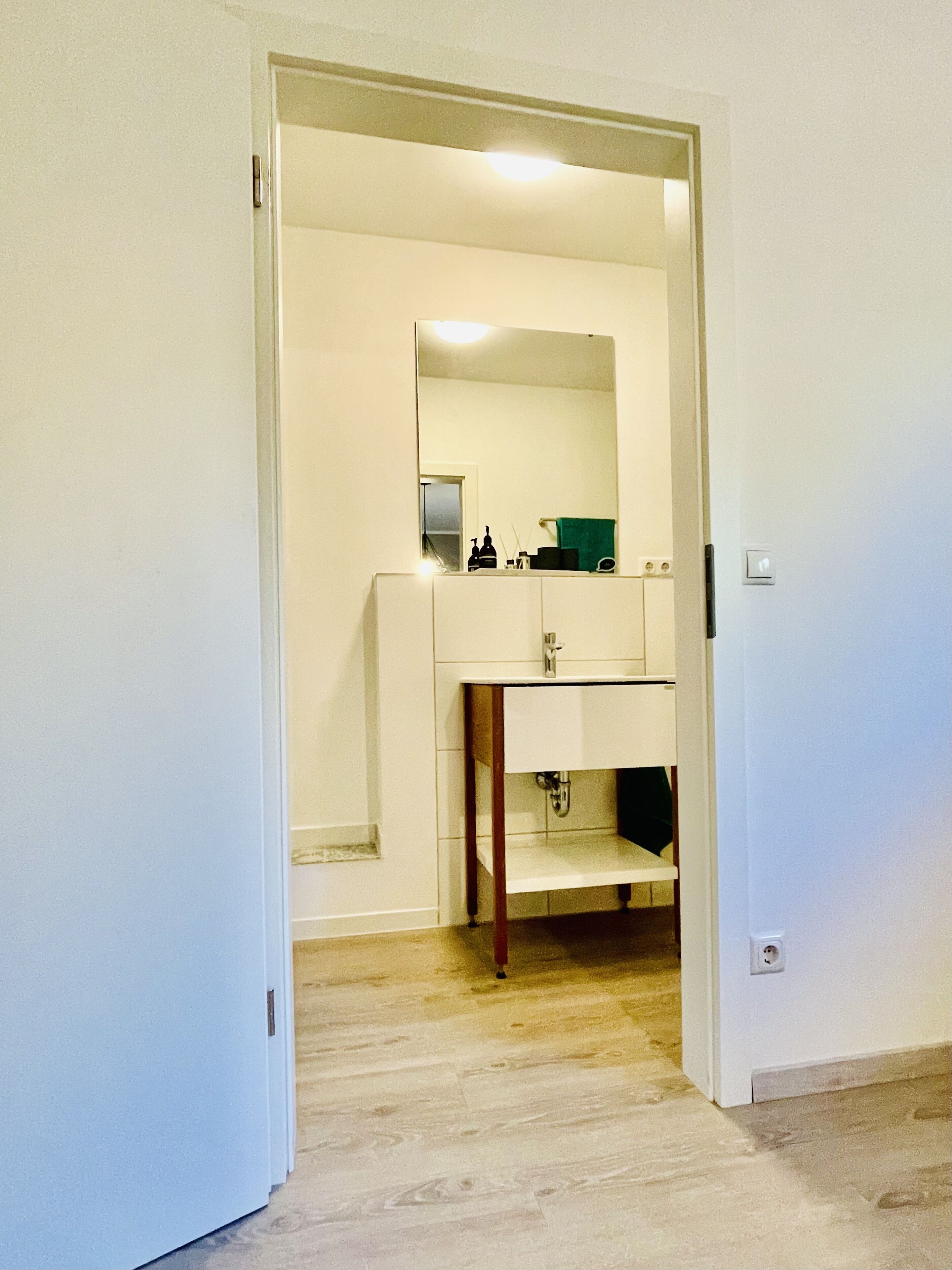 A bathroom with a white sink, mirror, and wooden vanity.
