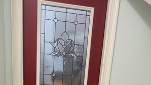 Una puerta roja con un panel de vidrio y un tirador de latón.