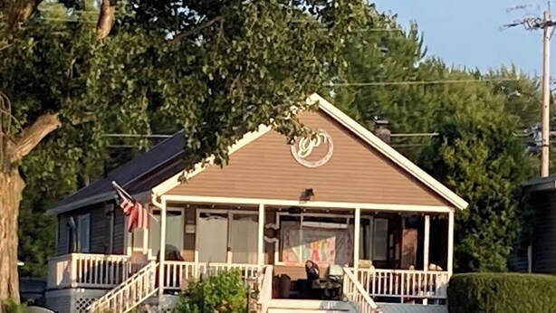 Een huis met een veranda, een trap en een kleine tuin.