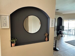 A modern interior with a large circular mirror, a potted plant, and a television in a living area. - 4 Bedroom Executive Villa with Pool & Spa, Games Room, Wifi and Large Garden
(Davenport)
