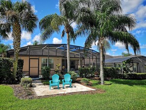 A house with a covered patio, two blue chairs, and palm trees. - 4 Bedroom Executive Villa with Pool & Spa, Games Room, Wifi and Large Garden
(Davenport)