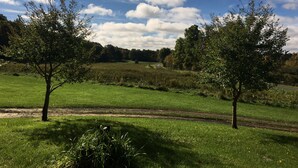 Een landelijk landschap met een onverharde pad, bomen en een grasveld onder een gedeeltelijk bewolkte lucht.