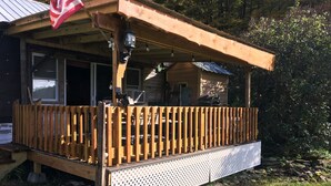 Een houten hut met een overdekte veranda en een metalen terras.