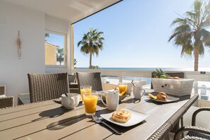 Enjoy a seaside breakfast on our sunny terrace with a view of palm trees and the ocean.