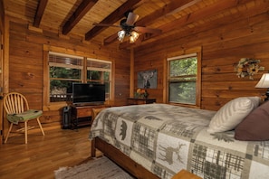 A wooden cabin bedroom with a bed, television, and a ceiling fan. - Hurricane Hideaway*Hot Tub*Game Rm*Views*PetsOK (Deep Gap)