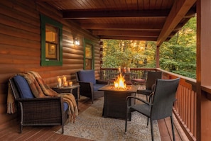 A wooden cabin with a covered porch, wicker furniture, a fire pit, and a view of autumn foliage. - Hurricane Hideaway*Hot Tub*Game Rm*Views*PetsOK (Deep Gap)