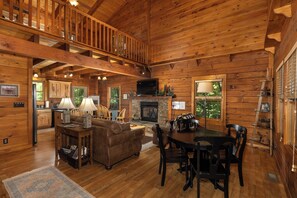 A log cabin interior with a dining area, living room, kitchen, and a fireplace. - Hurricane Hideaway*Hot Tub*Game Rm*Views*PetsOK (Deep Gap)