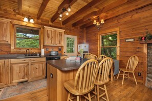 A wooden cabin interior with a kitchen, dining area, and large windows. - Hurricane Hideaway*Hot Tub*Game Rm*Views*PetsOK (Deep Gap)