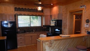 Una cocina con gabinetes de madera, un refrigerador, una estufa y una barra con taburetes.