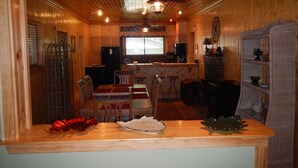 Una cocina acogedora con paredes de madera, una isla central con sillas, un refrigerador, un microondas y una estufa.
