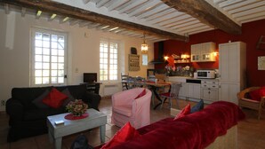 Una sala de estar acogedora con un sofá, un sillón y un comedor con mesa y sillas. Cuenta con una cocina con armarios y un microondas.