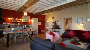 Amplia sala de estar con mesa de comedor, sillas, sofá y un sofá rojo.