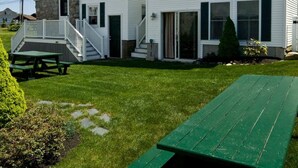 Ein zweistöckiges weißes Gebäude mit überdachter Terrasse und Picknicktisch.