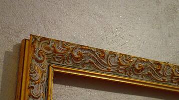 Un espejo con marco dorado y detalles decorativos sobre una pared con textura.