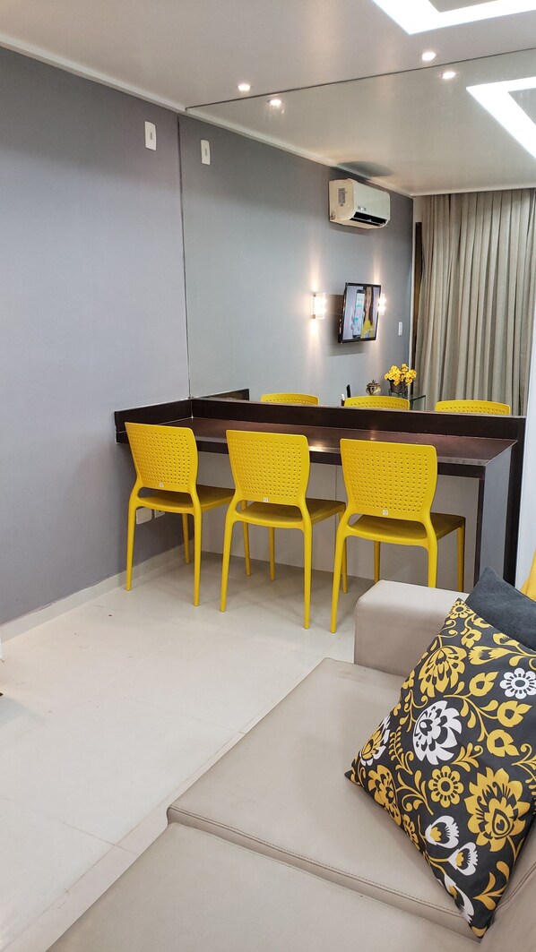 A modern dining area with a dark wooden table and four yellow chairs.