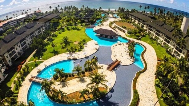 A resort with multiple swimming pools, palm trees, and a view of the ocean. - PORTO DE GALINHAS BANGALO PREMIUM AT THE BEACH CLASS HOTEL (ipojuca)