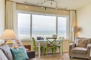Enjoy a room with a large window offering a view of the sea, a dining table, sofa, and chair, plus two lamps for added comfort.
