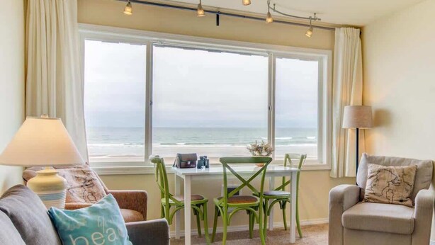 Una habitación con vistas al océano, una mesa de comedor con sillas, un sofá y un sillón.